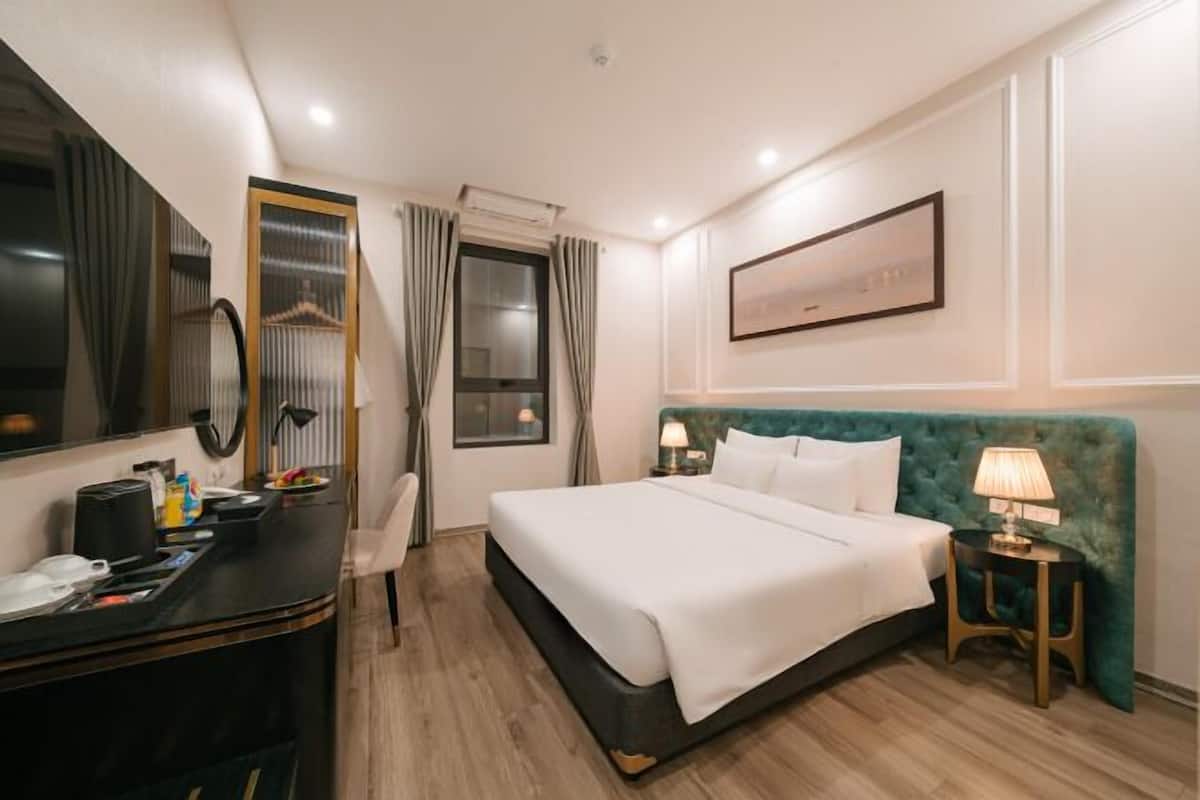 Una habitación de hotel con cama, mesita de noche, lámpara y un espejo grande.
