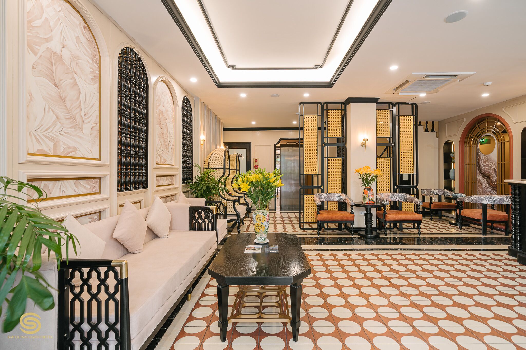 Un hall d’entrée spacieux, doté d’un sol à motifs, d’un canapé, d’une table basse et d’un coin salon avec des fauteuils et une table.