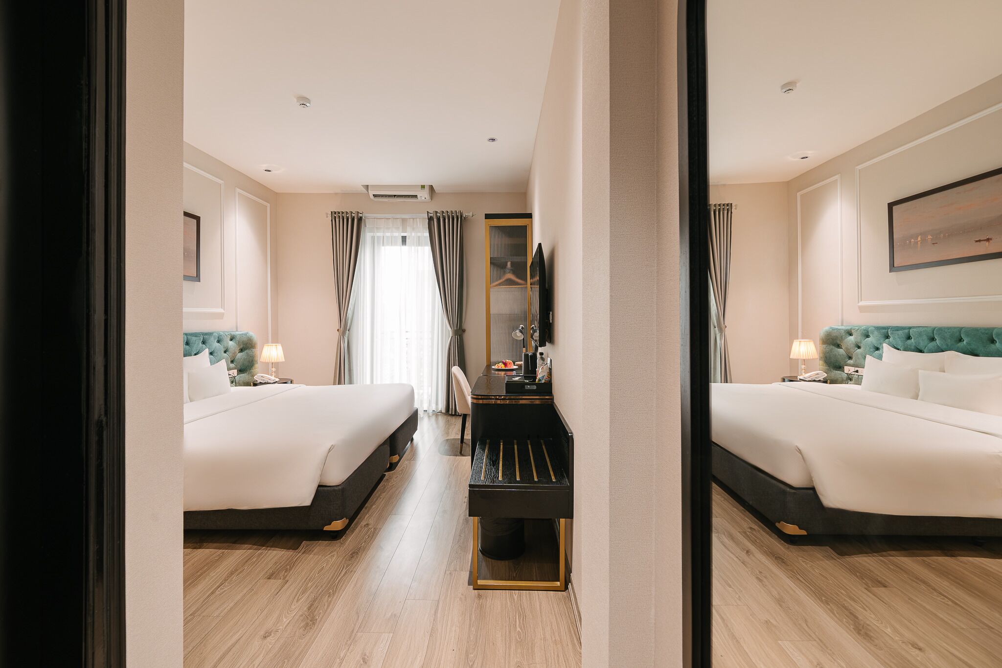 Una habitación de hotel con dos camas, un escritorio, un espejo y una ventana con cortinas.