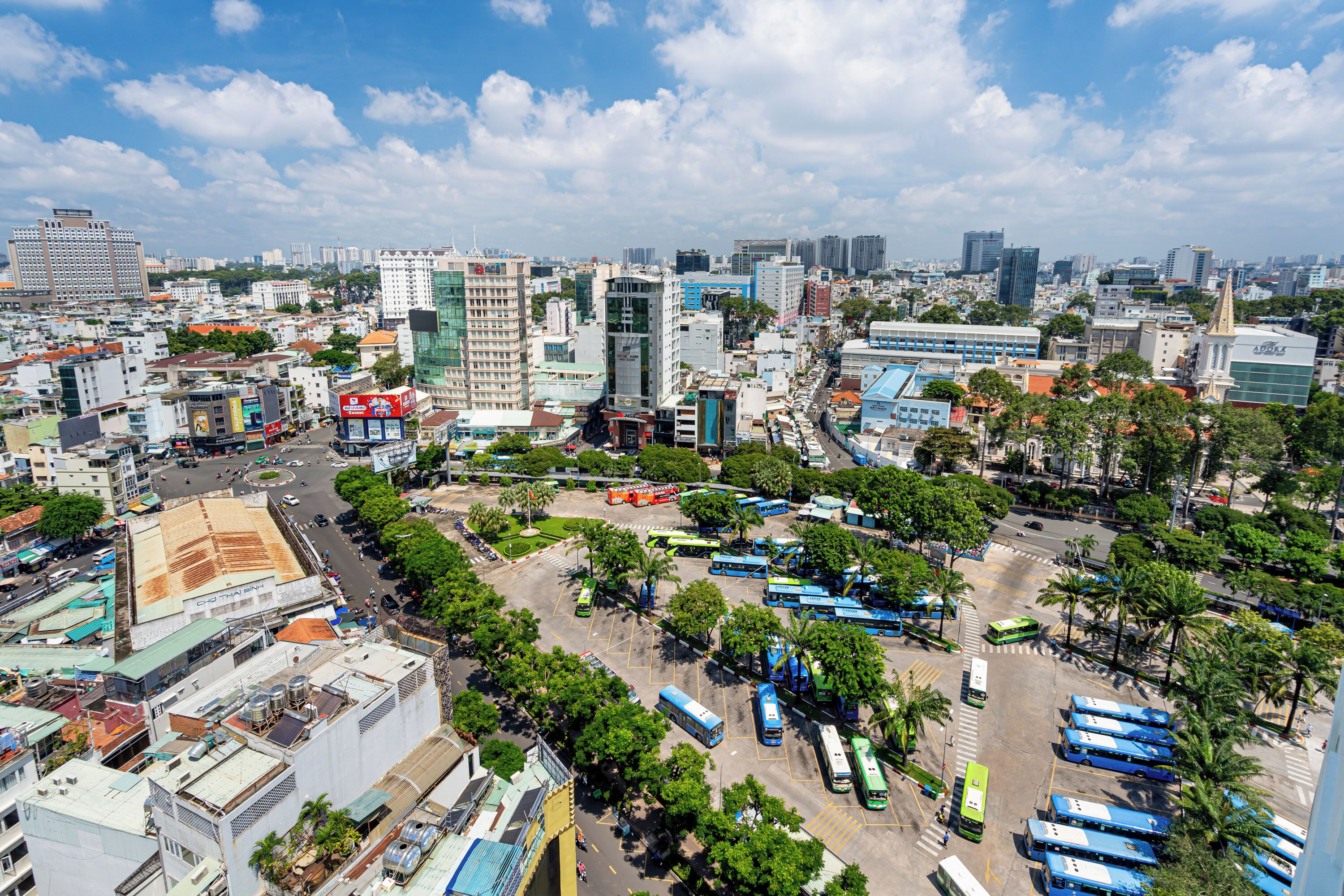 Un paisaje urbano con edificios modernos, un estacionamiento con autobuses y un cielo despejado.