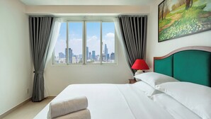 Une chambre d’hôtel avec un grand lit, une vue sur les gratte-ciel de la ville, une lampe rouge et un tableau au mur.