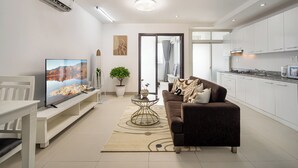 Un salon moderne avec un téléviseur à écran plat, un canapé, une table basse et une plante en pot.