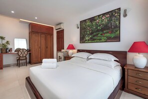 Una camera d'albergo con un letto, comodini, una scrivania, un armadio e un quadro appeso al muro.