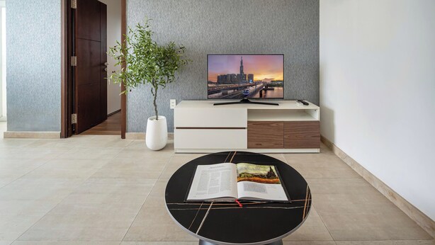 Une chambre moderne dotée d’un téléviseur à écran plat, d’une table à manger avec un magazine, d’une plante en pot et d’une console au design minimaliste.