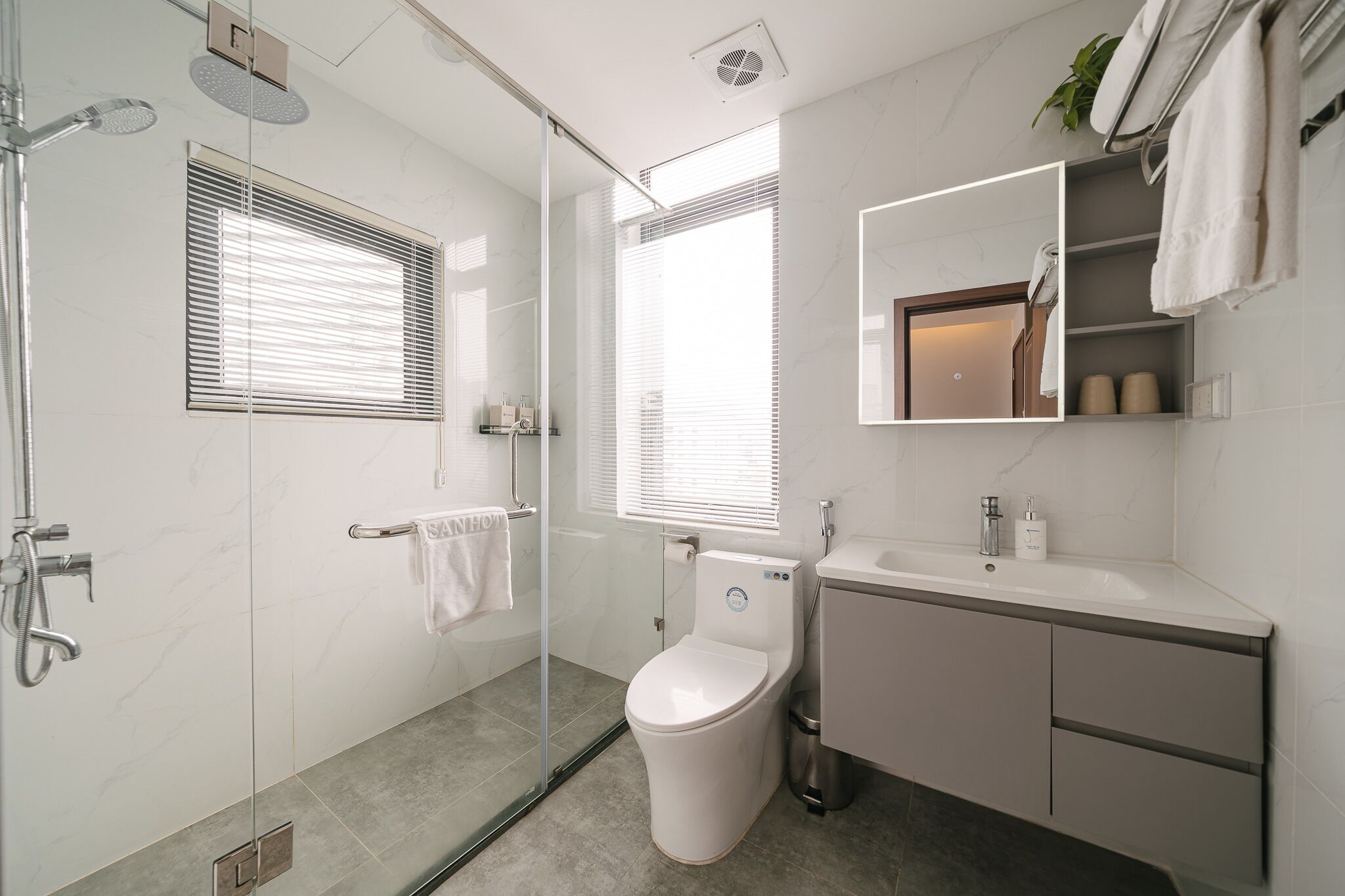 Une salle de bain moderne avec une douche à parois de verre, des toilettes, un lavabo et un miroir.