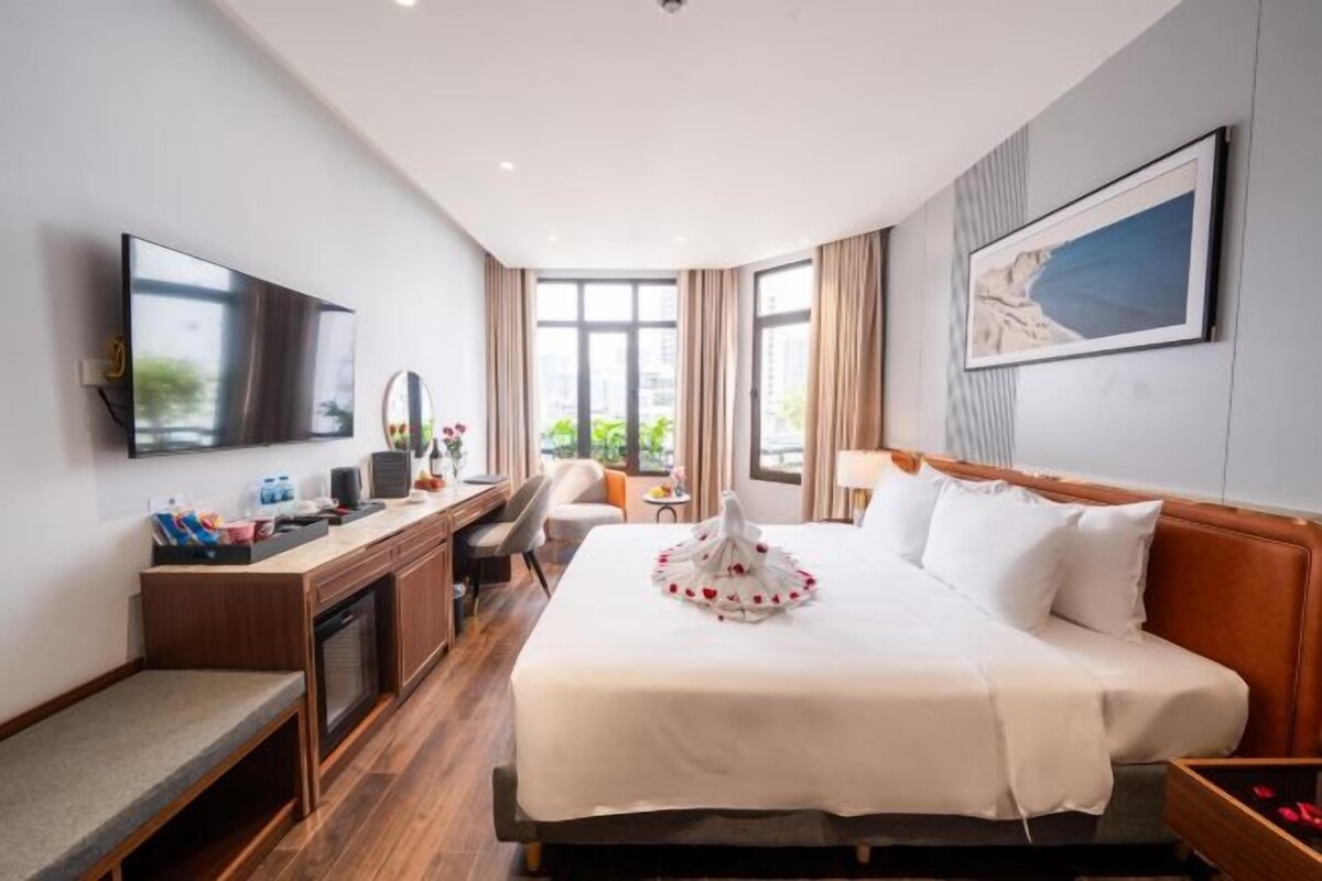 A hotel room with a bed, desk, TV, and a view of the outdoors.