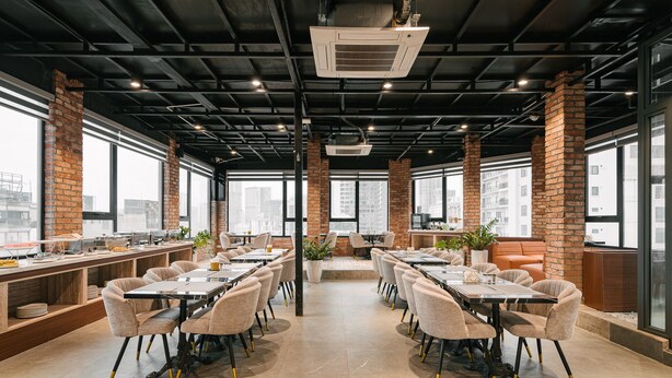 A modern dining area with brick walls, large windows, and multiple tables and chairs. - San Seize Hanoi Hotel (Hanoi)