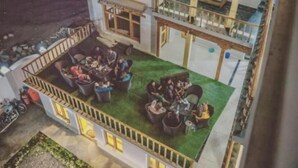 Een gebouw met twee verdiepingen en een dakterras. Het terras heeft buitenmeubels en een klein zwembad.