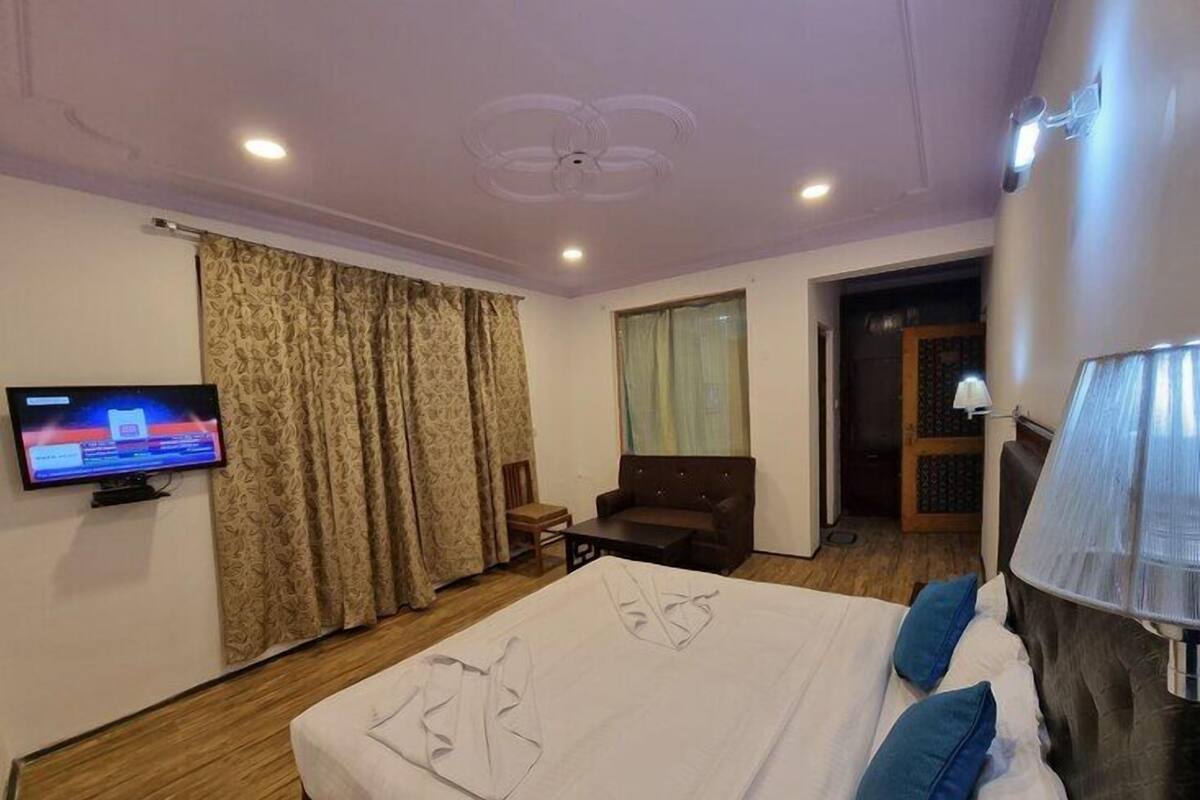 A hotel room with a bed, a TV, a desk, and a chair.