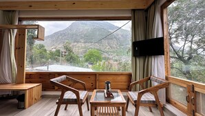 A wooden-framed room with a large window, a table, and two chairs. - Crimson inn by Senderos De Pine (Kullu)