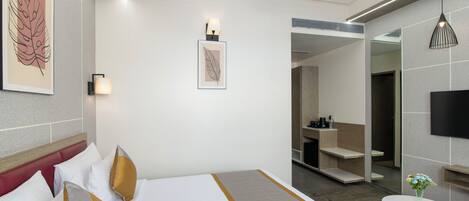 A hotel room with a bed, bedside tables, a mirror, a TV, and artwork on the walls.