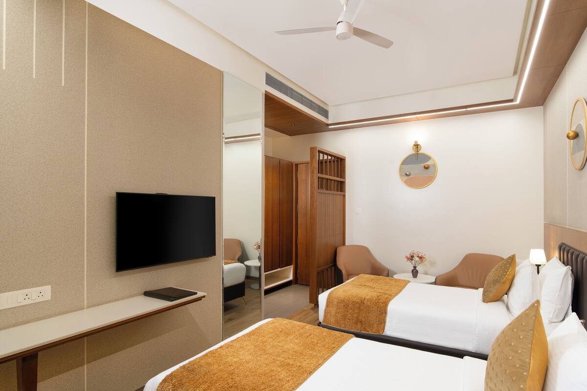 Une chambre d’hôtel avec deux lits, une télévision, un bureau et un miroir.