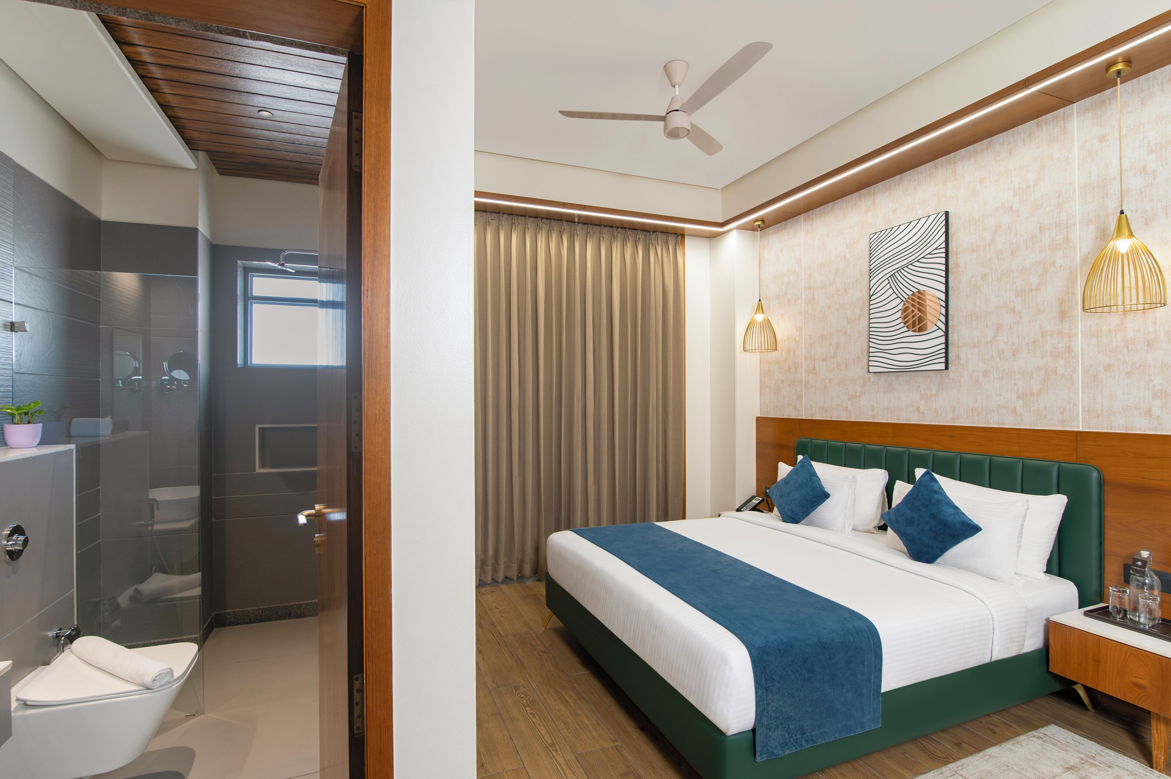 A hotel room with a large bed, a bedside table, a ceiling fan, a shower, and a window with curtains.