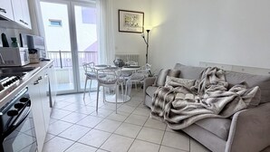 A modern kitchen with a stove, microwave, and dining area with chairs and a table. - Bixio Leisure Flexrent - Abyssinia (Riccione)
