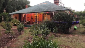 A brick house with a sloped roof, a chimney, and a porch with steps leading to the entrance. - Cosy and comfortable riverside homestead in Bridgetown - sleeps up to 14 guests. (Bridgetown)