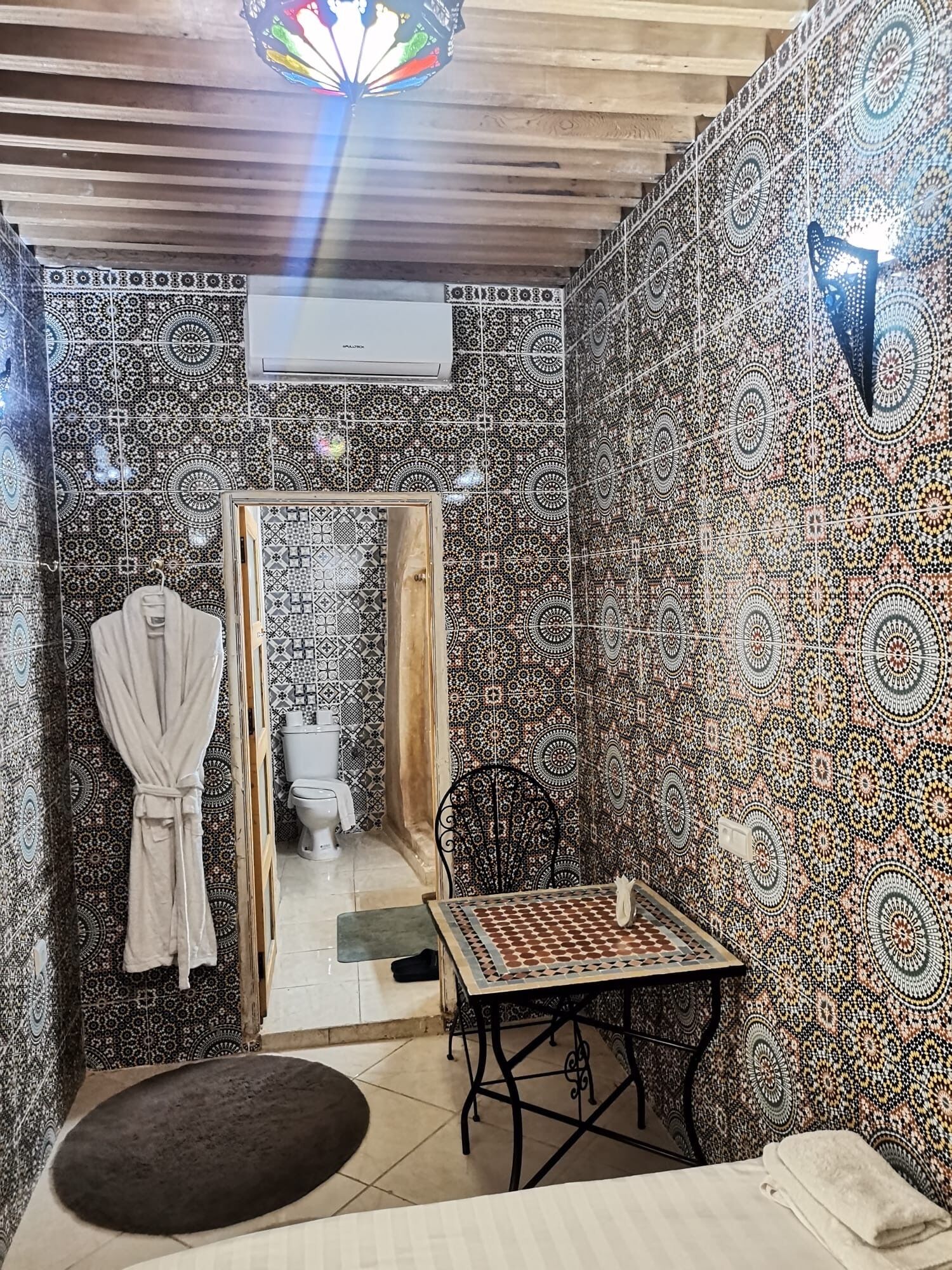 A bathroom with patterned tiles, a mirror, a sink, and a towel rack.