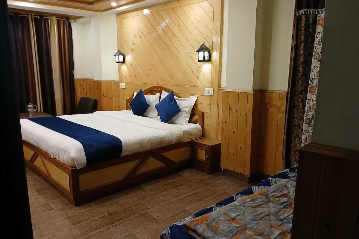 A wooden-paneled room with a large bed, two bedside tables, and two wall-mounted lamps.