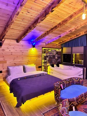Relax in this inviting bedroom with a large bed, armchair, and small table, surrounded by natural textures and a bathtub.