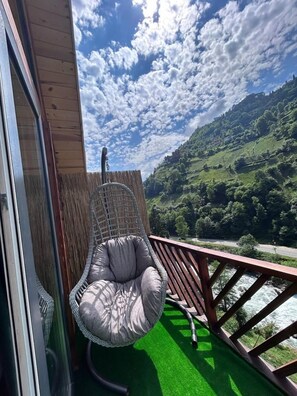 Enjoy the serene river views from this balcony, featuring a wicker chair and artificial turf floor.