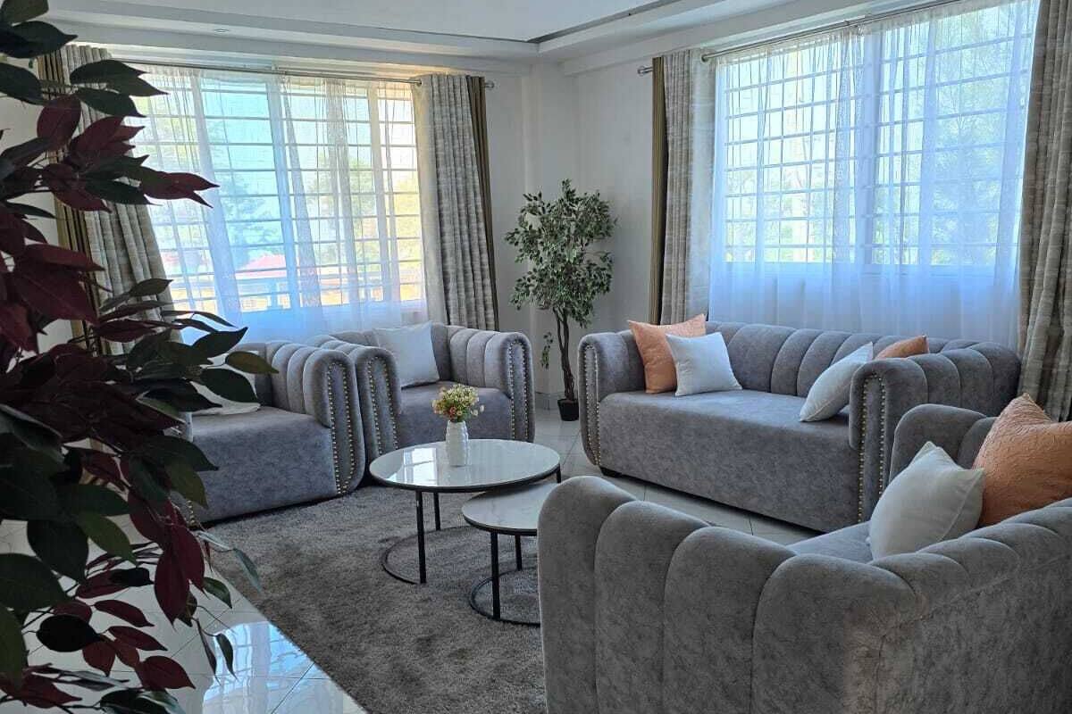 A spacious living room with grey sofas, a coffee table, and a potted plant.