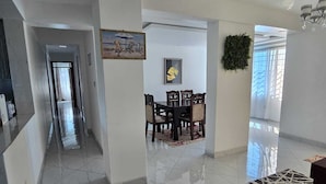 Un amplio pasillo con comedor que incluye una mesa y sillas, un cuadro en la pared y un candelabro.