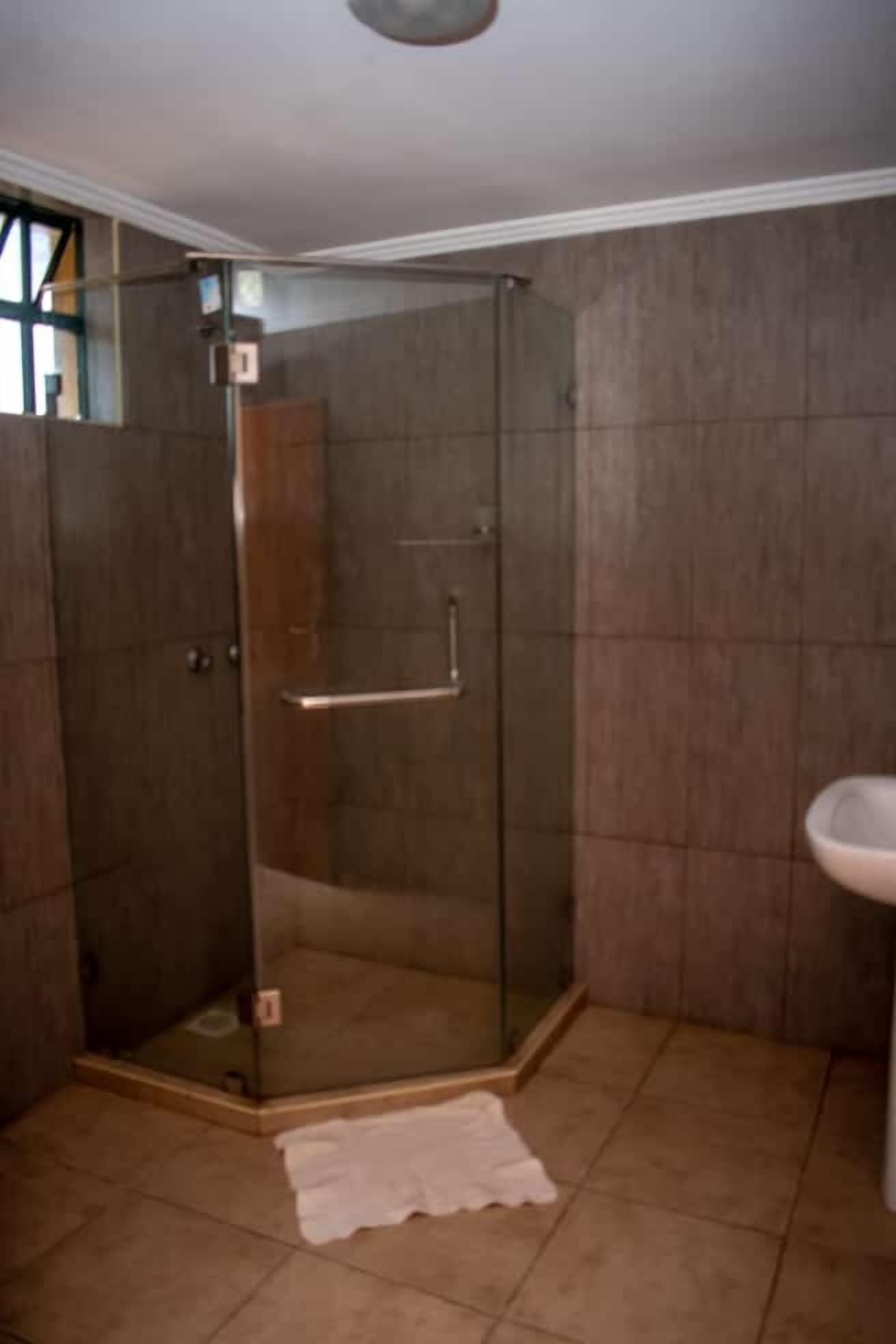 A bathroom with a glass shower enclosure, a white sink, and tiled walls.
