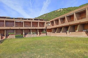 Un edificio de varios pisos con balcones, un patio interior y un paisaje montañoso de fondo.