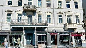 Un edificio de varios pisos con una entrada central, ventanas amplias y un balcón en el segundo piso.