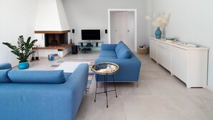 A modern living room with a blue sofa, a TV, and a fireplace. - Villa Rossini with swimming pool - My Rental Homes (Custonaci)