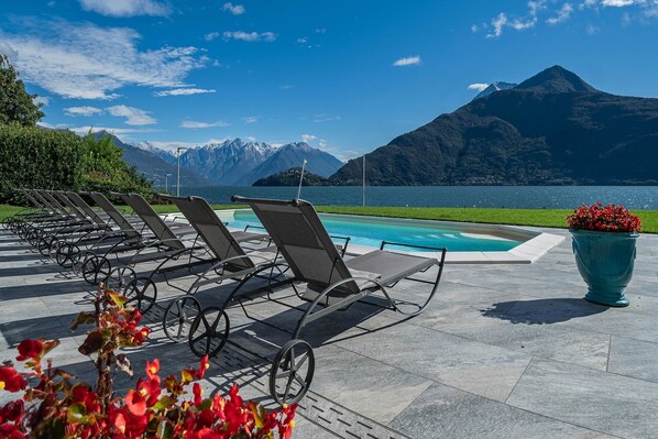 Un espace aménagé au bord de la piscine, avec des chaises longues et un pot de fleurs.