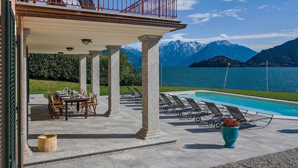 A poolside area with a view of mountains and a lake.