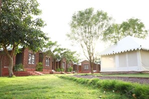 A row of brick buildings with a white tent-like structure in the background. - Impian Resort (Jodhpur)