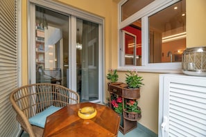 Un comedor con una mesa de madera, una silla de mimbre y plantas en macetas.