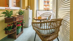 A balcony with wicker furniture, potted plants, and a view of a building. - Tu chiamale emozioni  3 suites (Rome)
