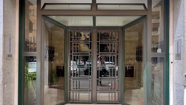 A hotel entrance with a glass door and a metal gate. - Tu chiamale emozioni  3 suites (Rome)