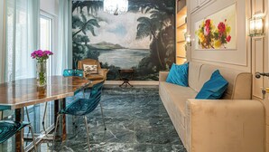 A dining area with a wooden table, blue chairs, a vase with flowers, and a mural of a tropical scene on the wall. - Tu chiamale emozioni  3 suites (Rome)