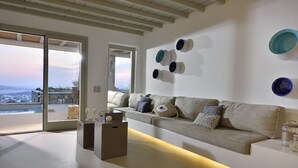 Een moderne woonkamer met een bank, decoratieve borden en uitzicht op zee.