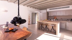 Een moderne keuken met een centraal eiland, barkrukken en een hanglamp.