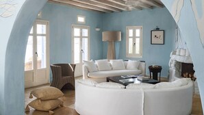 Une pièce avec un canapé blanc, un lampadaire et une grande fenêtre.