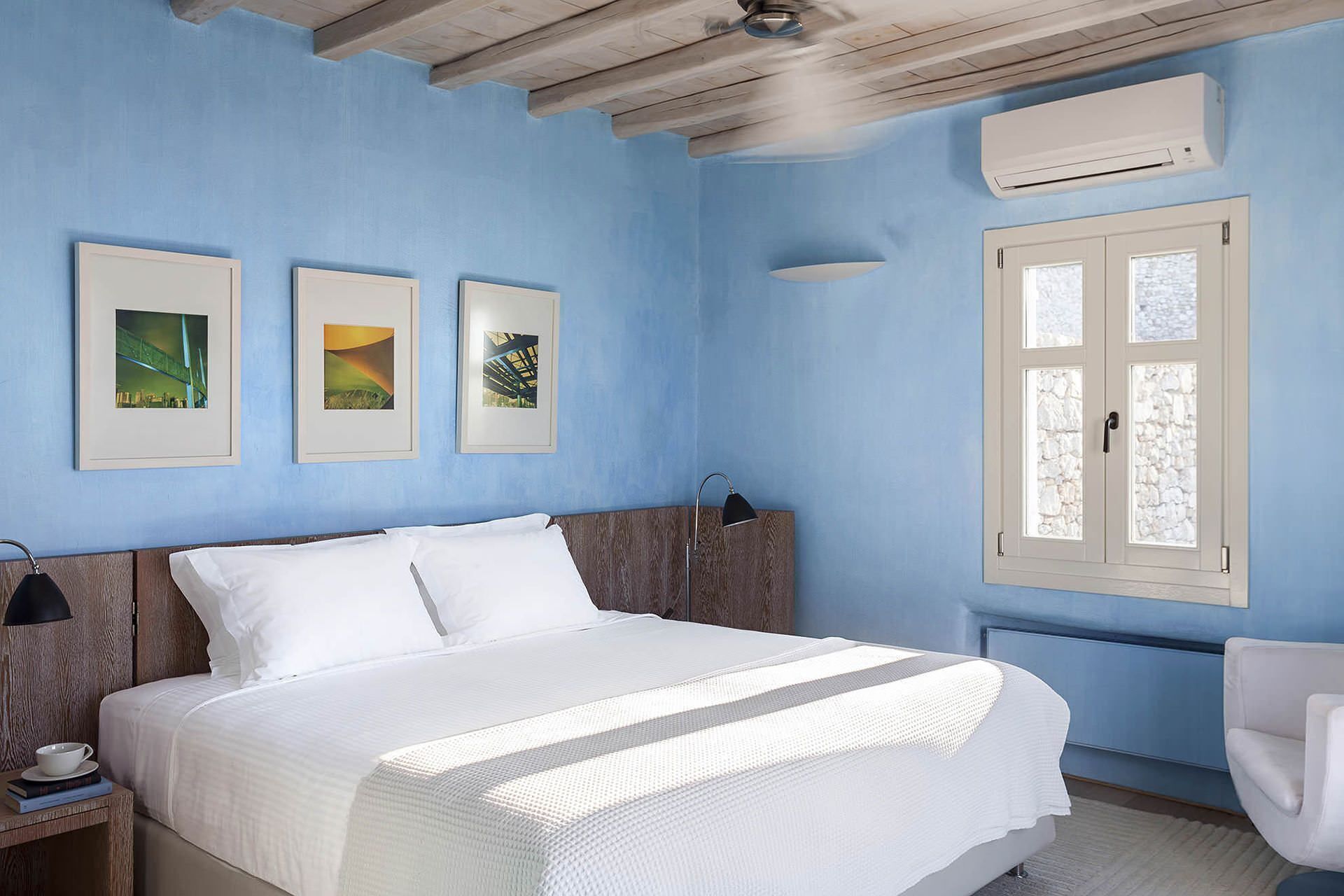 A bedroom with a bed, a nightstand, a lamp, and a window with a view.