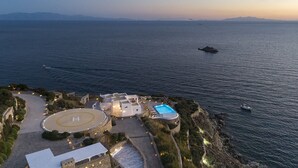 An aerial view of a coastal resort with a swimming pool, a helipad, and a boat in the water. - My Rental Homes - Efkalia with infinity pool, panoramic views and private dock (Mykonos)