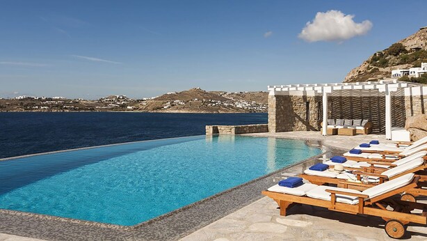 A poolside area with lounge chairs and a pergola overlooking a coastal landscape. - My Rental Homes - Efkalia with infinity pool, panoramic views and private dock (Mykonos)