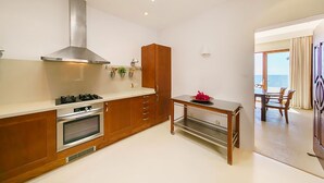 Una cocina moderna con electrodomésticos de acero inoxidable, armarios de madera y un comedor con vistas al mar.