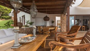 Una mesa de madera para comer con sillas, un sofá blanco y un pilar de piedra.