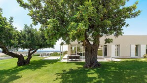 A modern house with a patio, a dining area, and a view of the landscape. - Green Hill with pool and terrace - My Rental Homes (Noto)