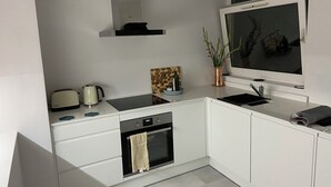 Eine moderne Küche mit weißen Schränken, einem eingebauten Backofen, einem Kochfeld und einem Fenster über der Spüle.