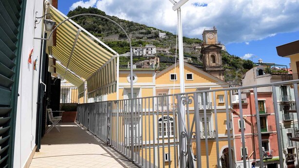 Un balcon donnant sur une colline, avec des bâtiments et un clocher.