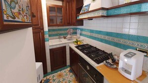 Une cuisine avec des meubles en bois, une cuisinière à gaz, un évier et une machine à café.