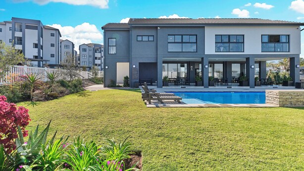 Una casa moderna de dos pisos con piscina, césped cuidado y zona de patio.