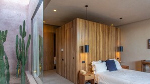A modern bedroom with a wooden panel wall, a bed with white bedding, two bedside tables, and a cactus plant in a glass container.